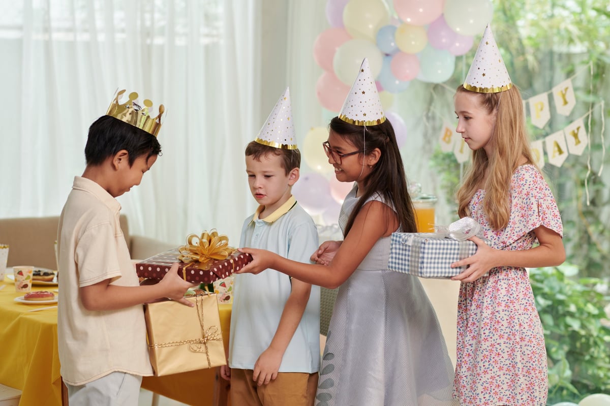 A happy kid wearing a paper crown while accepting birthday presents