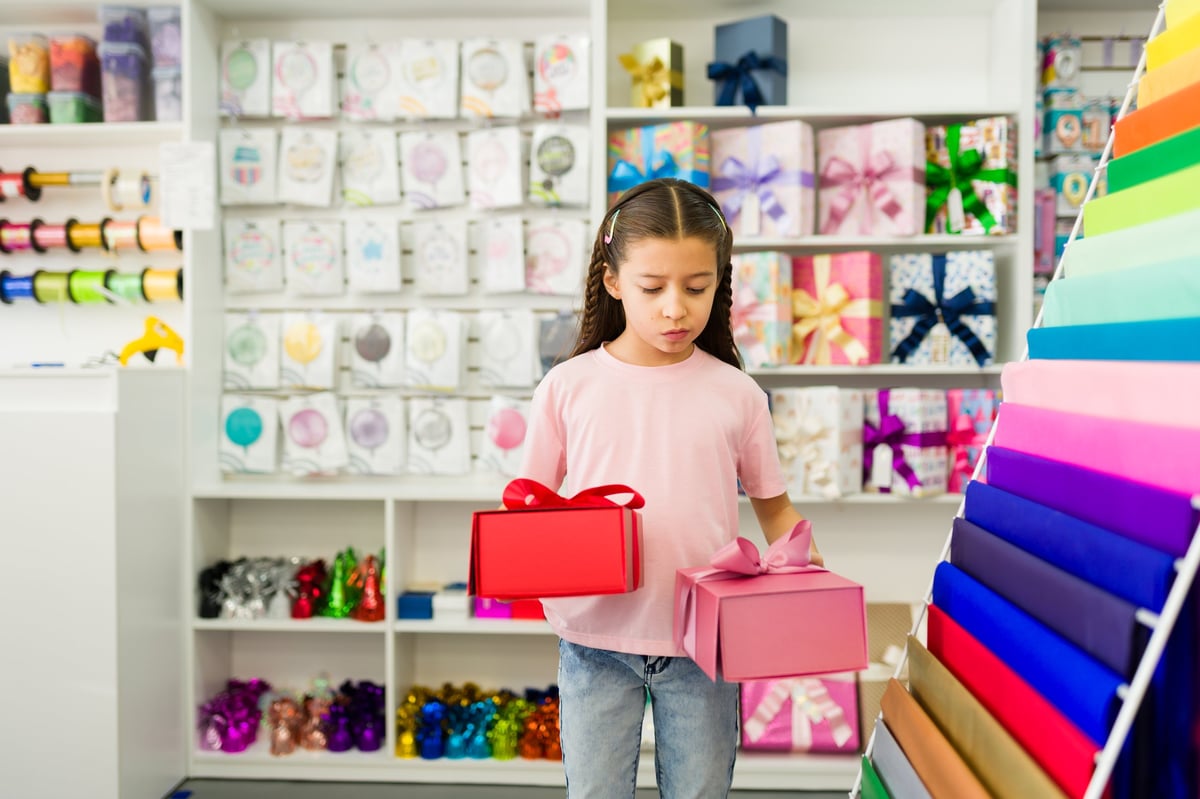 A girl comparing red and pink gift boxes, choosing the perfect present