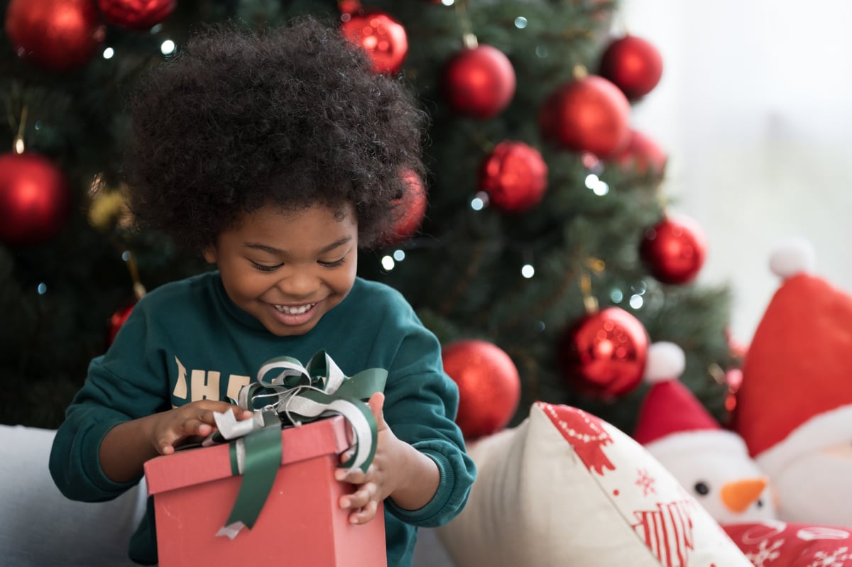 A smiling little boy holding a gift box on Christmas morning