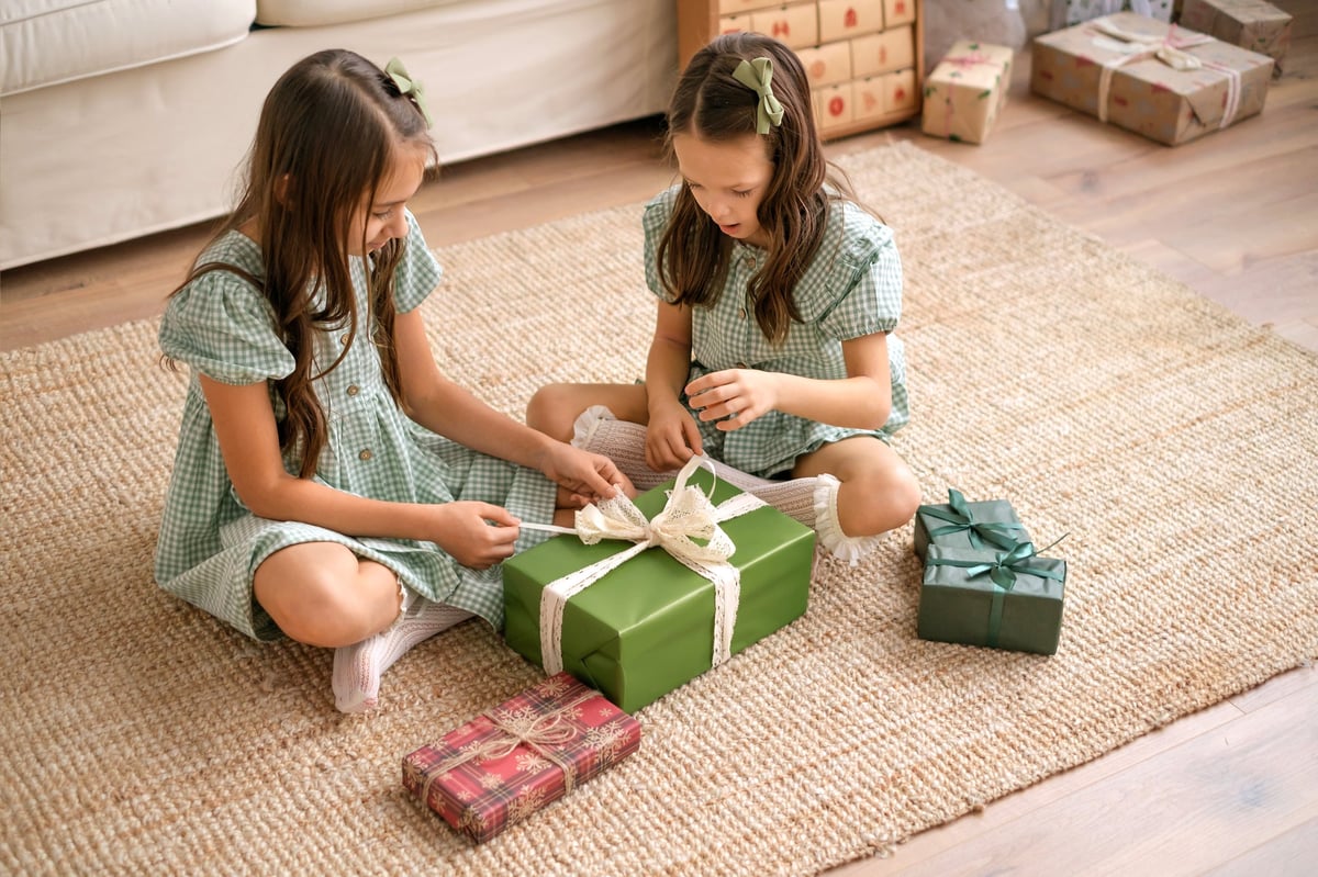 Children untying a bow on a large gift box